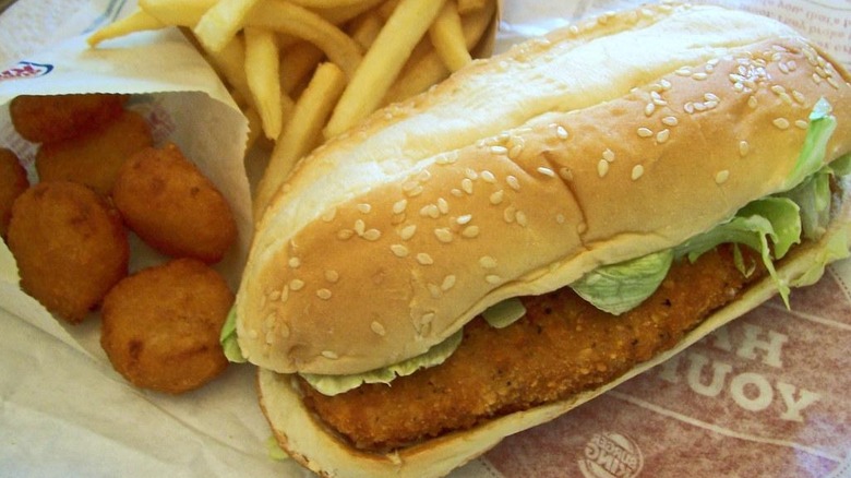A Burger King original chicken sandwich with some french fries and nuggets on the side