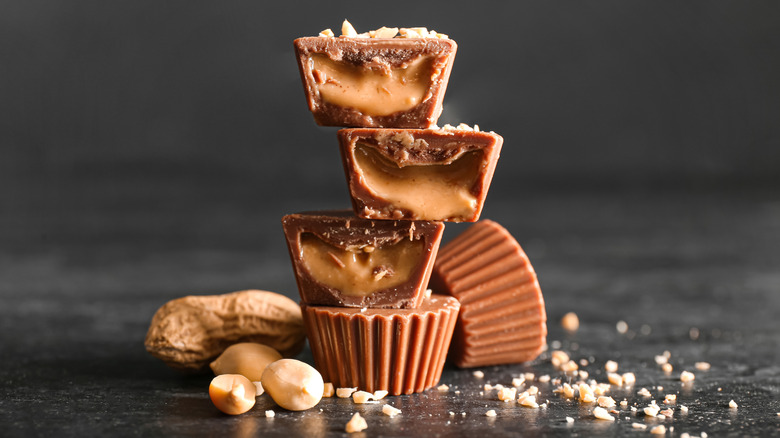 chocolate peanut butter cup candies topped with chopped nuts on dark background