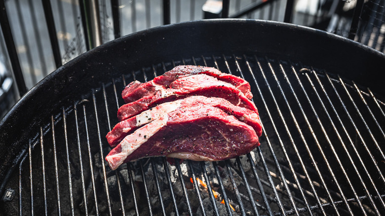 Uncooked picanha steaks on grill, standing fat side down
