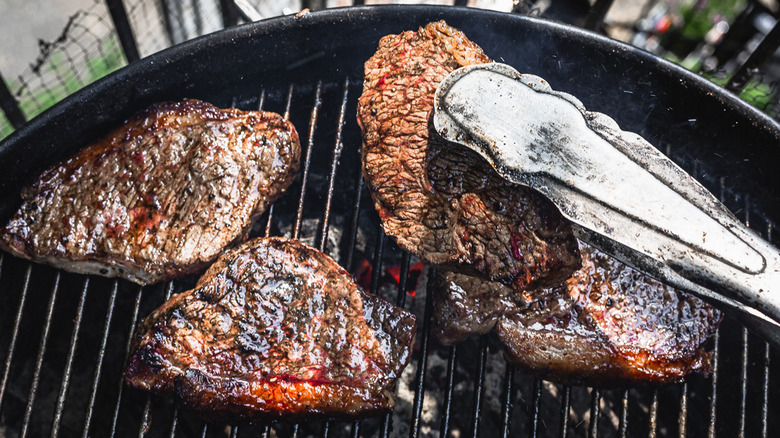 Lifting a whole picanha steak from grill
