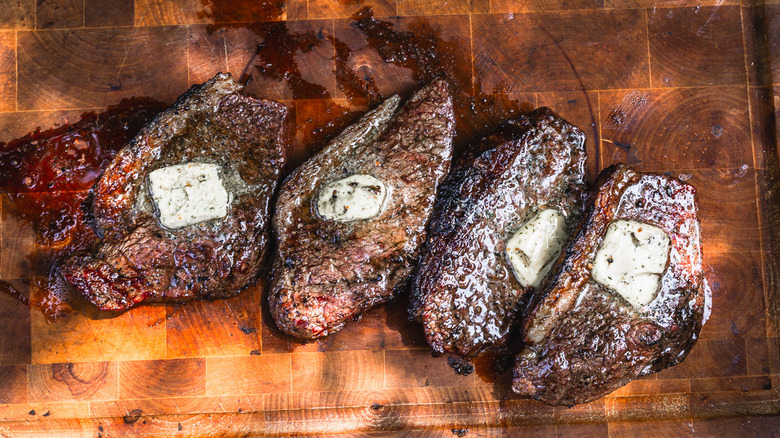 Whole picanha steaks with garlic butter on cutting board