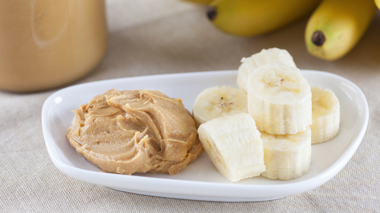 A white plate with peanut butter and sliced banana