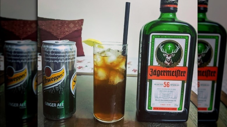Jägermeister mixed with ginger ale, between a can of ginger ale and a bottle of Jägermeister