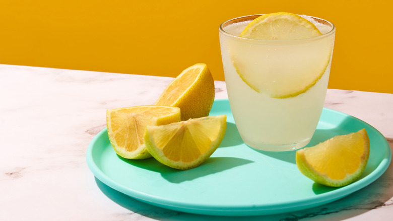 A glass of lemonade next to slices of lemon