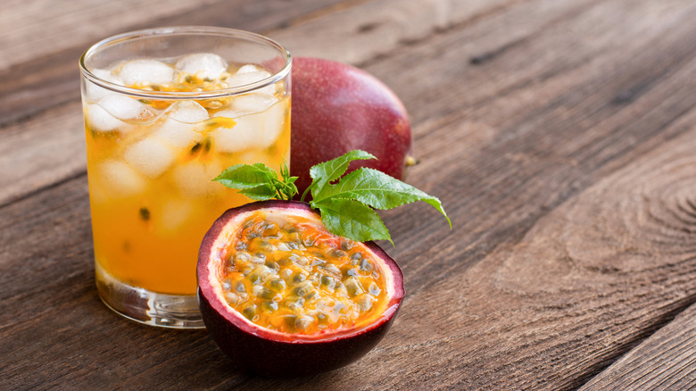 A tumbler of passion fruit juice among pieces of passion fruit