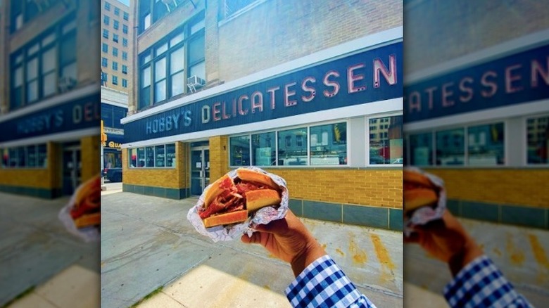 Hobby's Deli sign hand holding corned beef sandwich