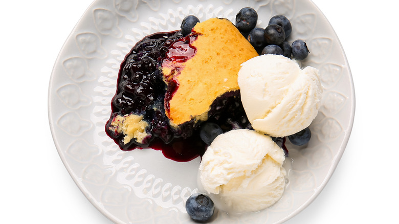 Blueberry cobbler on a white plate with vanilla ice cream