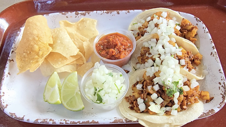 Potato and soy chorizo tacos on a white tray with chips at Disneyland