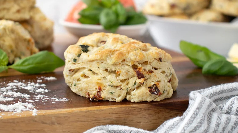Basil and Tomato Biscuits on wooden board with flour and basil