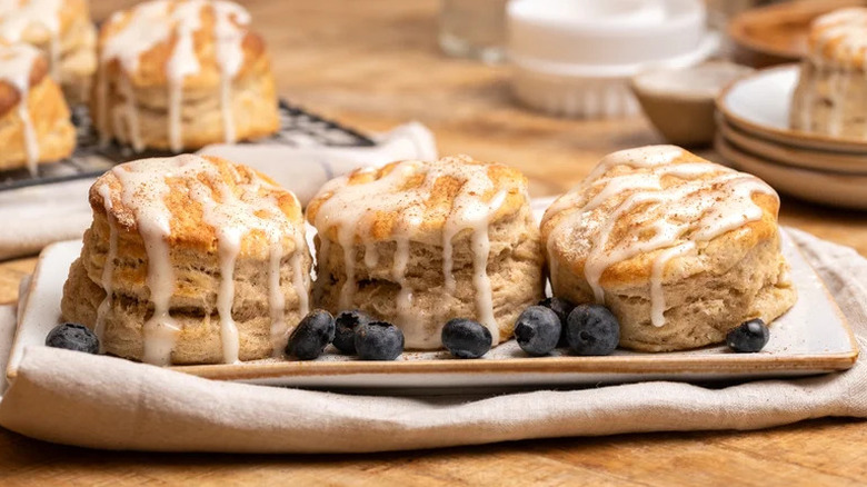 Easy Flaky Cinnamon Biscuits arranged on rectangular plate with blueberries
