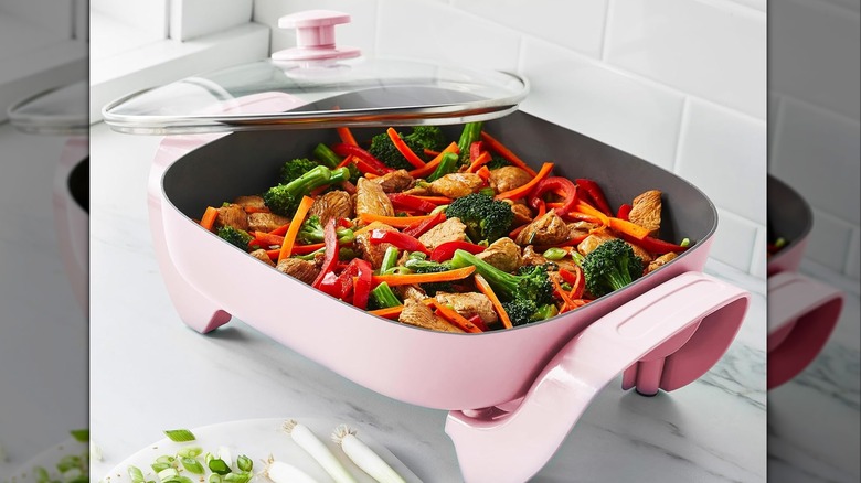 A pink GreenLife electric skillet with mixed vegetables