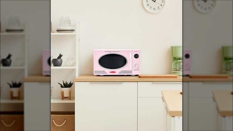 A pink Nostalgia microwave in a cream kitchen