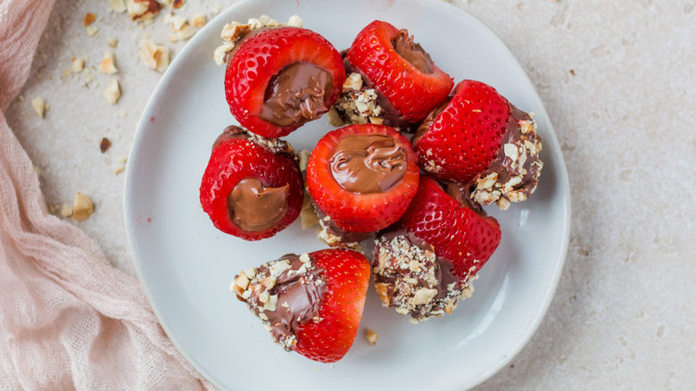 Nutella-stuffed strawberries on plate, with chopped hazelnut coating