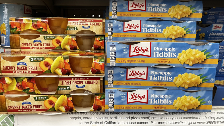 Clear plastic fruit cups in assorted varieties stacked on a refrigerated shelf