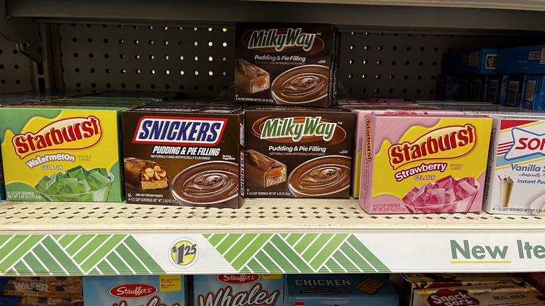 Assorted cups of pudding and gelatin desserts lined up on a store shelf