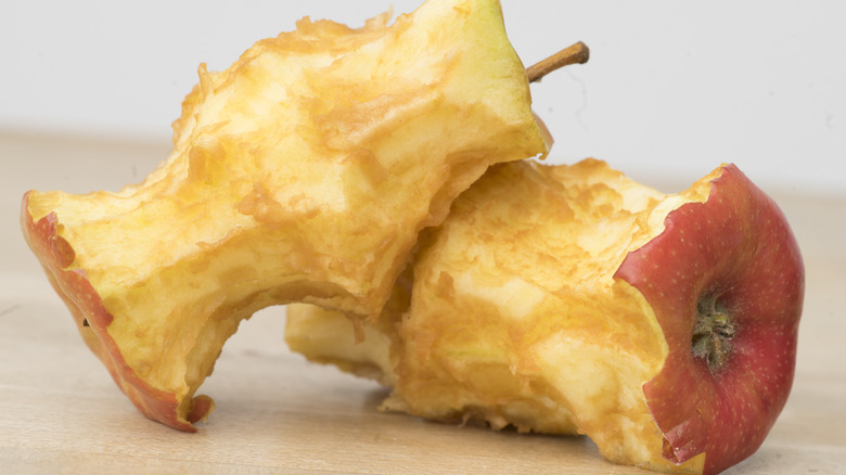 A close up of two apple cores with one resting on top of the other