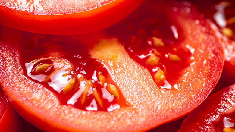 A close-up of a freshly cut tomato, showing the seeds inside that could be planted