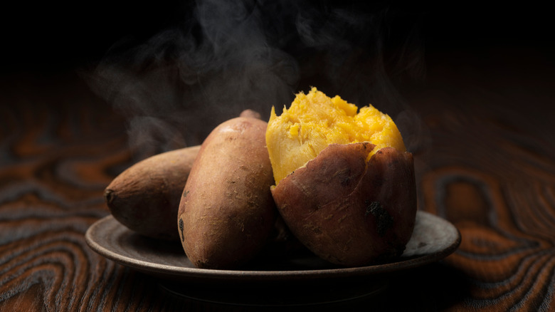Baked sweet potatoes on a plate, with steam rising from them