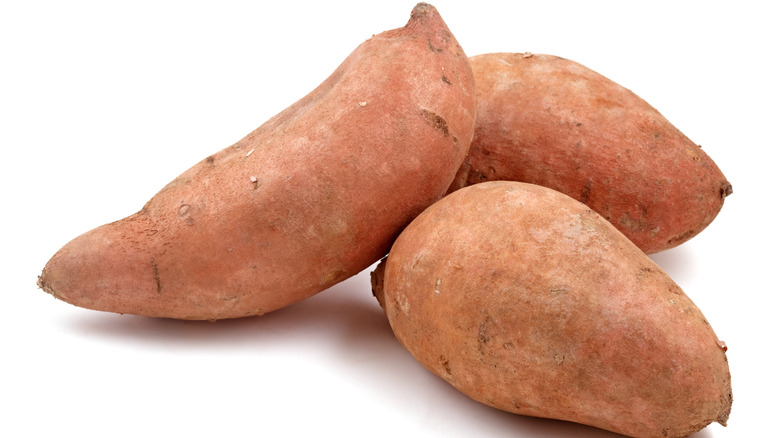 Three sweet potatoes against white background