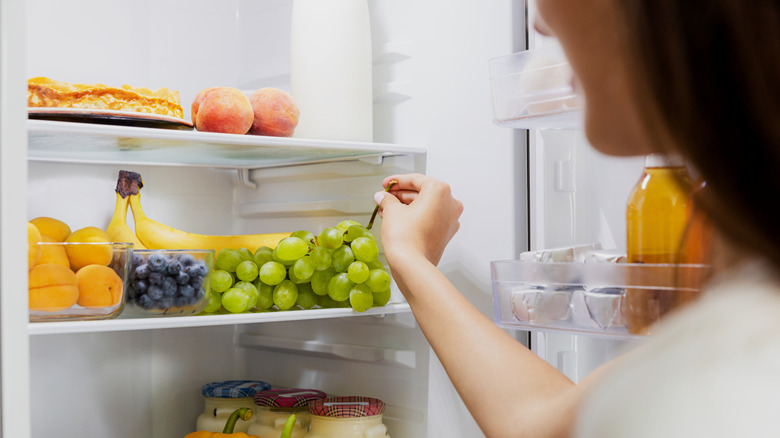 Woman reaching into fridge