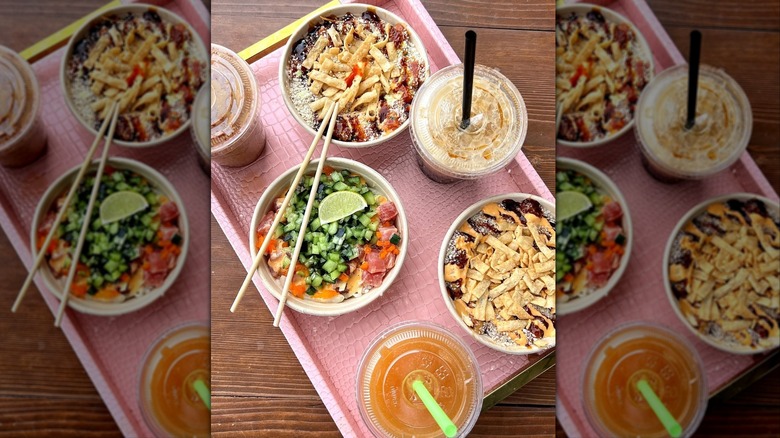 Top view of poke bowls and cocktails on tray