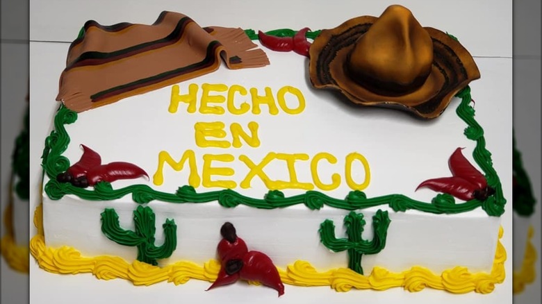 Rectangular Hecho in Mexico cake with piped cream depicting chilis, saguaros, a sombrero, and a poncho