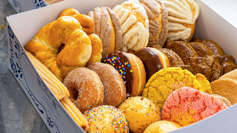 A box of Mexican treats including cuernos, donuts, and conchas