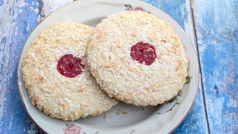Two coconut cookies with jam filling on plate