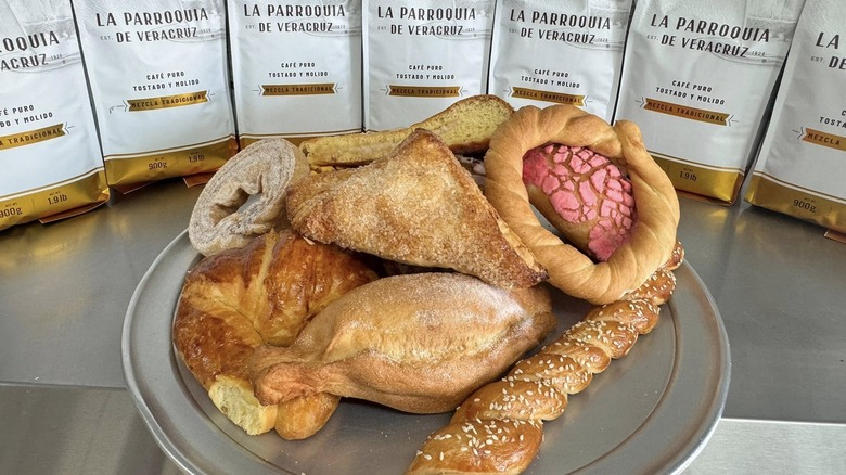 Assorted pan dulce on plate with bags of La Parroquia de Veracruz coffee in the background