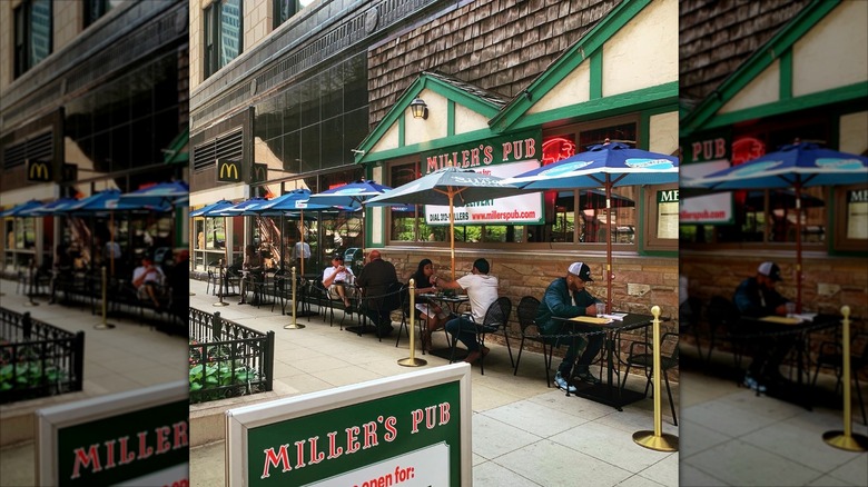 Exterior of Miller's tub with tables outside under umbrellas and customers