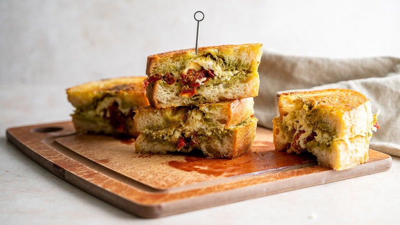 Pesto grilled cheese sandwich slices on wooden board