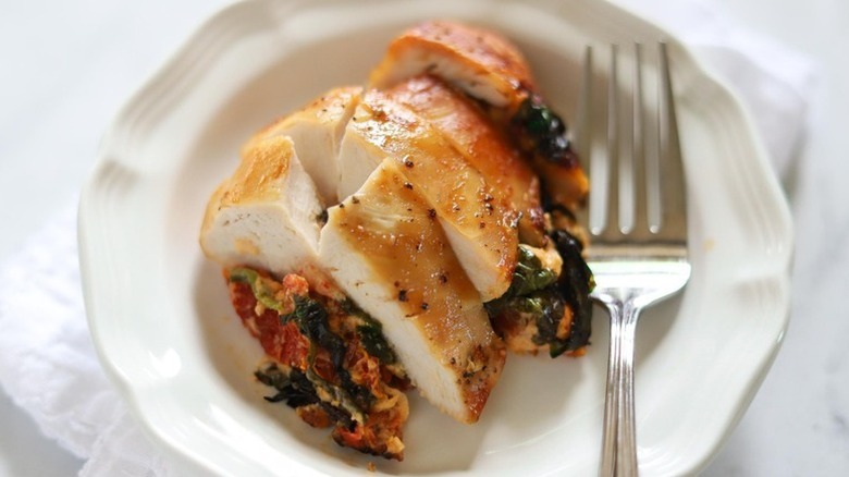 Spinach and sun-dried tomato-stuffed chicken breast on plate with fork