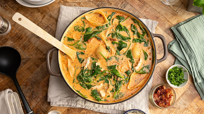 Pot of creamy chicken pasta soup with spinach and sun-dried tomatoes