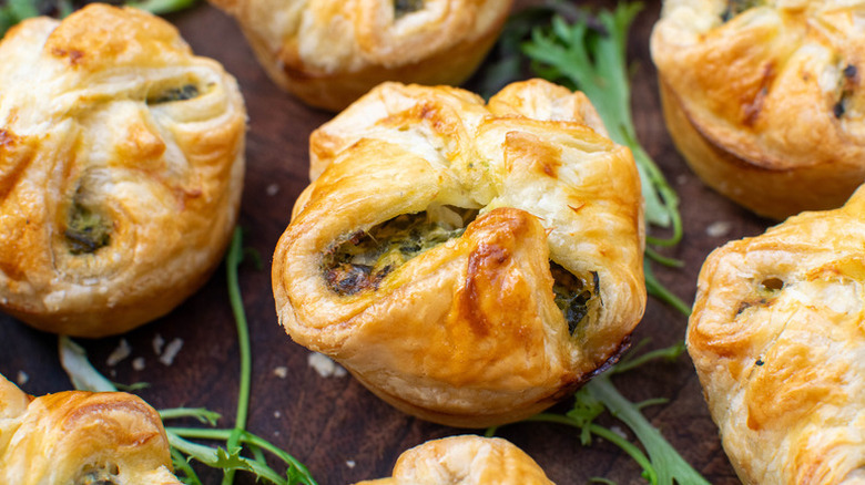 Spinach-filled pastry puffs on wooden surface