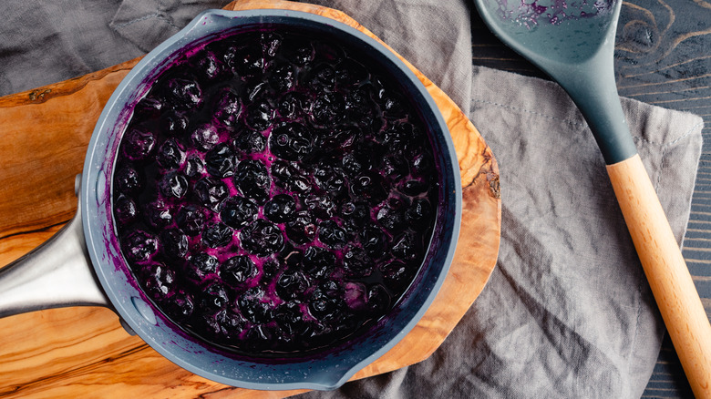 pot full of slightly crushed blueberries on serving platter with spoon and napkin