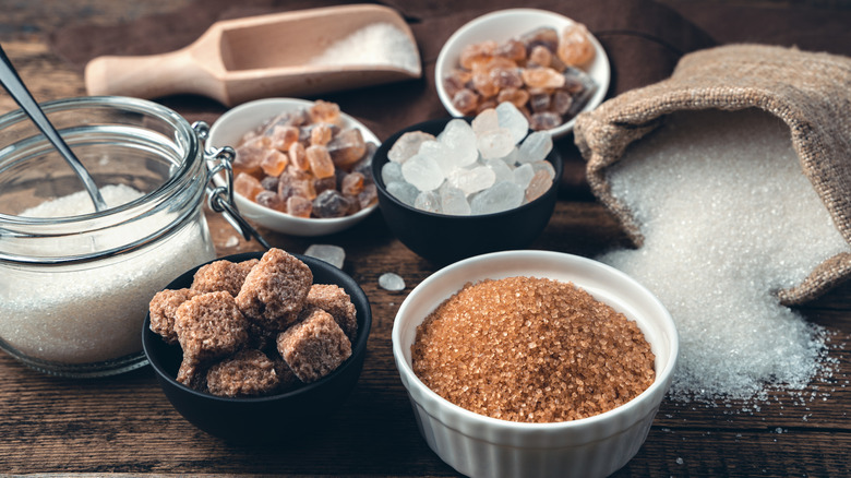 Several types of granulated and cubed sugar on wooden surface