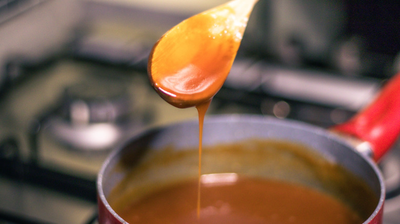 Spoon dripping caramel back into pot on stovetop