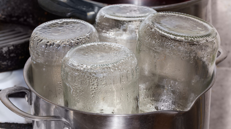 Glass jars being sterilized with steam in pot