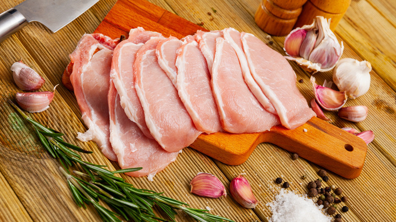A row of very thin pork loin chops on a wooden cutting board