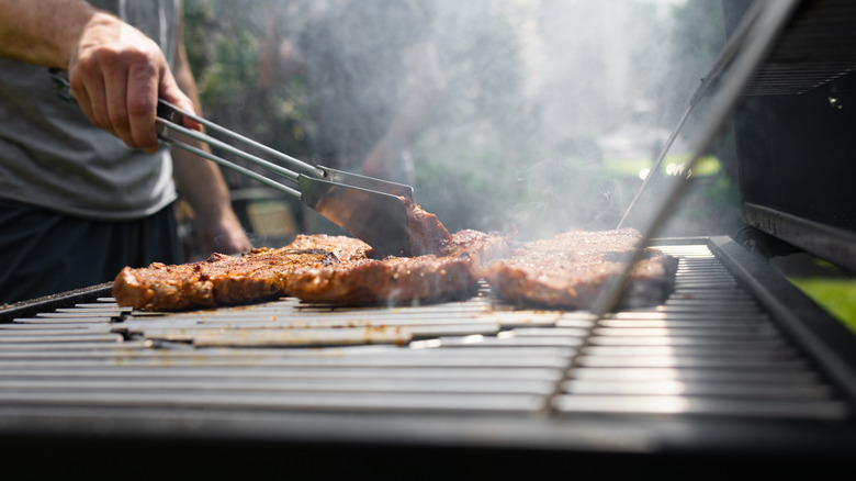 Man cooking pork chops on a backyard grill