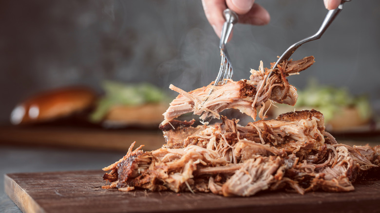 Forks picking apart pulled pork