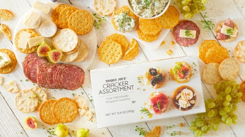 Various crackers, fruits, meats, and spreads on table