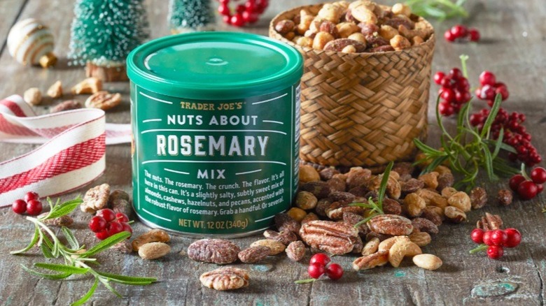 Can of nuts on table alongside nuts, fresh sprigs of rosemary, and Christmas decor