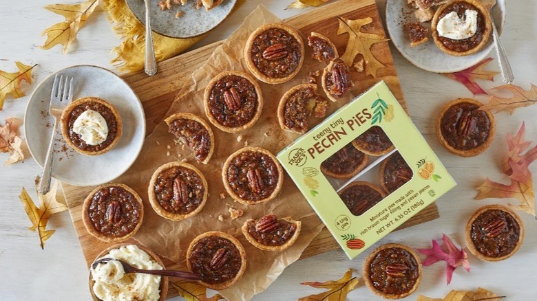 Mini pecan pies on cutting board surrounded by leaves