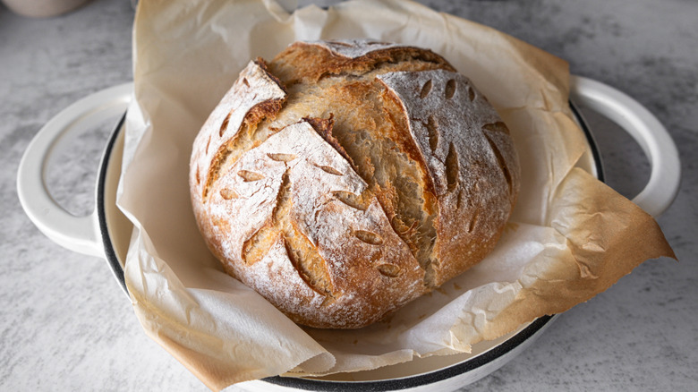 top view of round sourdough loaf in dutch oven on parchment paper