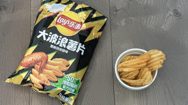 Overhead image of bag of Lay's Roasted Chicken Wing flavored potato chips with small white ramekin filled with chips