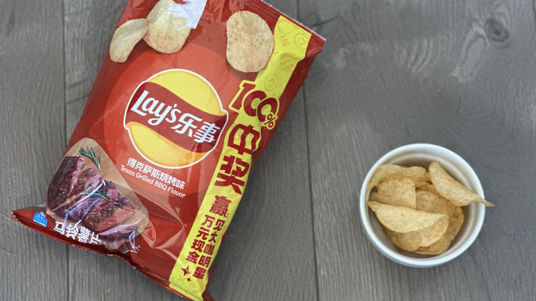 Overhead image of bag of Lay's Texas Grilled BBQ flavored potato chips with small white ramekin filled with chips