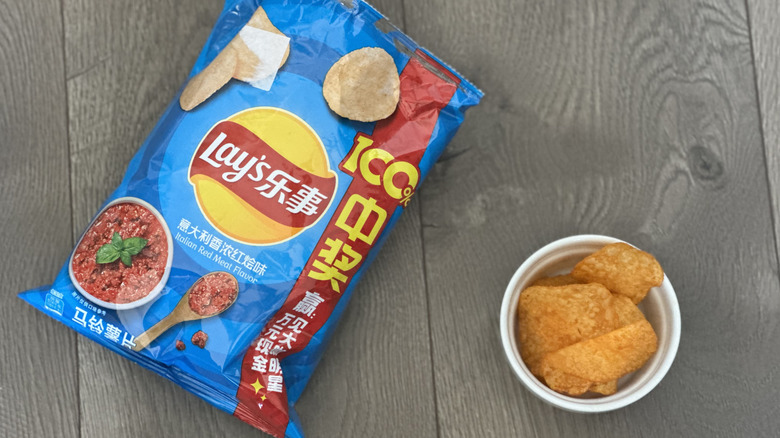 Overhead image of bag of Lay's Italian Red Meat flavored potato chips with small white ramekin filled with chips
