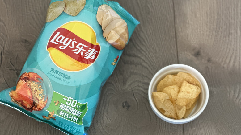 Overhead image of bag of Lay's Fried Crab flavored potato chips with small white ramekin filled with chips