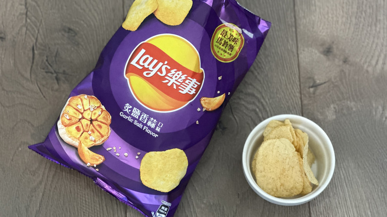 Overhead image of bag of Lay's Garlic Salt flavored potato chips with small white ramekin filled with chips
